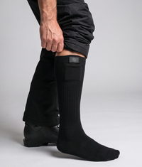 ColdCarve heated socks in black, worn under ski trousers with the trouser leg lifted